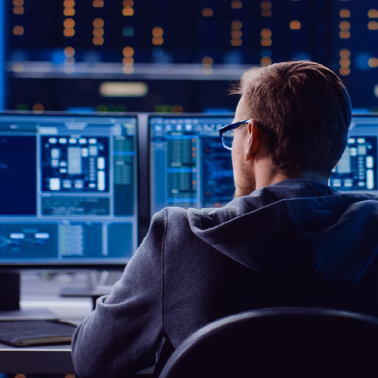 man wearing glasses working on two computers